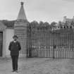 View of man standing in front of wrought iron entrance gates to Kinpurnie Castle