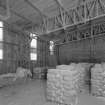 Interior view from SE of corner of lime store (a former aircraft hangar), showing corner uprights of latticed steel girders forming the internal frame of the building