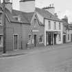 View of north side of Victoria Street, Kirkpatrick Durham, from south west, showing the Crown Hotel and R McAllister's shop (no.8)