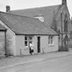 View of north side of Victoria Street, Kirkpatrick Durham, from south west showing Victoria Cottage and the Free Church and a woman with child