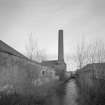 General view from S of works, showing Brothock Burn, and E end of boiler house and associated chimney.