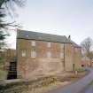 View of mill from SE, showing lade and water wheel on left, mill in centre and one of the two kilns on right.