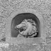 Former stable block, carved horse's head in alcove above door, detail