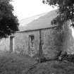 View from SW of front elevation showing harled rubble walls and corrugated iron roof.