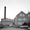 View from S of rear of works, including boilerhouse chimney.