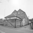 General view from N of the NE end of the works, showing the N gable of the High Mill, and the offices and gatehouse in the foreground.