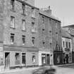 General view of the west side and 76-92 Buccleuch Street, Edinburgh, seen from the south east, showing the premises of a newspaper agent, a cycles shop, Caledonian Photographers, a hairdresser and Eclipse Motor Cycles.