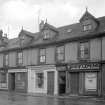 View of 10-18 Glasgow Street, Ardrossan, from NW, showing the premises of The Horse Shoe, City of Glasgow Friendly Society, A Cunningham & Son ironmongery and hardware shop, and John Fleming.