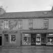 View of 42-44 Glasgow Street, Ardrossan, from NW, showing D Robertson electrician and the Sutter clothes shop.