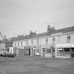 General view of Princes Street, Ardrossan, from SE, showing Scottish Gas Board, Mac's Bar, Seamus Gents Hairdresser and Kerr & Co.