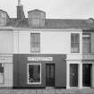 View of 7-11 Princes Street, Ardrossan, from SW, showing a general store and cycle shop.