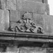 Detail of monogram and crest at base of chimney-stack above main entrance on W front.