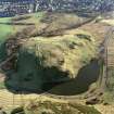 Oblique aerial view of Holyrood Park centred on the remains of a fort, field bank and scooped settlement, taken from the NNW.