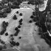 Oblique aerial view, taken from the WSW, centred on the country house, formal gardens and stables.