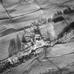 Oblique aerial view centred on the farmhouse and farmsteading with the remains of the scooped settlement adjacent, taken from the SW