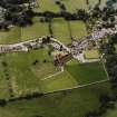 Oblique aerial view of New Abbey centred on the abbey with the abbey wall adjacent, taken from the NE.