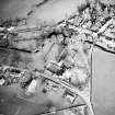 Oblique aerial view of Kirkgunzeon centred on the church, churchyard, manse and road bridge, taken from the SW.