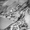 Oblique aerial view of Kirkgunzeon centred on the church, churchyard, manse and road bridge, taken from the ESE.