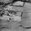 Oblique aerial view centred on the burial-ground with church and burial-ground adjacent, taken from the SE.