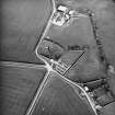 Oblique aerial view centred on the remains of the church and burial-ground with buildings and enclosures adjacent, taken from the W.