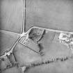 Oblique aerial view centred on the remains of the church and burial-ground with buildings and enclosures adjacent, taken from the S.