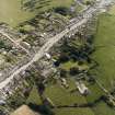 Oblique aerial view centred on the remains of the priory and burial ground with the church and village adjacent, taken from the N.