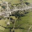 Oblique aerial view centred on the remains of the priory and burial ground with the church and village adjacent, taken from the NW.