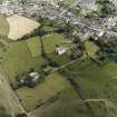 Oblique aerial view centred on the church with the remains of the priory and burial ground and the village adjacent, taken from the W.