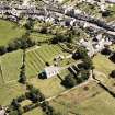 Oblique aerial view centred on the church, burial ground and remains of the priory, taken from the W.