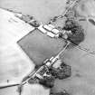Oblique aerial view centred on the farmstead with standing stones adjacent, taken from the WNW