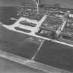 Oblique aerial view of Crail Airfield centred on the remains of the control tower, buildings, huts and aircraft hangars, taken from the ESE.