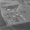 Oblique aerial view of Crail Airfield centred on the remains of buildings, a water tank and a hut, taken from the WSW.