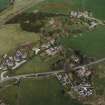 Oblique aerial view of the village centred on the burial-ground, manse and the remains of the church with the farmsteading adjacent, taken from the SW.