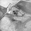 Oblique aerial view centred on the remains of the church and the graveyard, taken from the E.