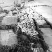 Oblique aerial view centred on the hospital and churches, with the farmsteading adjacent, taken from the SW.
