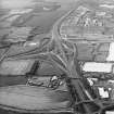 Oblique aerial view centred on the motorway interchange with the industrial estate adjacent, taken from the SSE.