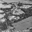 Oblique aerial view centred on the church, burial ground and village, taken from the WSW.