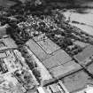 Oblique aerial view centred on the church and burial ground with remains of works adjacent, taken from the WNW.