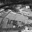 Oblique aerial view centred on the church and burial ground with remains of works adjacent, taken from the SSE.