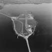 Aerial view, Orkney, Lamb Holm taken from the SW.  Visible is the modern grass landing strip, Lamb Holm World War II coast battery, the concrete hut bases of the former prisoner-of-war camp, the Italian Chapel and parts of Churchill Barriers Nos. 1 and 2.