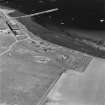 Aerial view of Orkney, Hoy, Lyness, Royal Naval Oil terminal, view from SW, of the site of the torpedo depot with a group of air raid shelters, generator house and several ancillery buildings. The former recreation centre, NAAFI and pier are in the background.