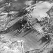 Oblique aerial view centred on the farmhouse, byre, farmsteading and the remains of the earthwork and farmstead, taken from the N.