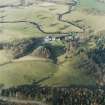 Oblique aerial view centred on the country house with stables and bridge adjacent, taken from the S.