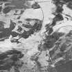 Oblique aerial view centred on the remains of rig with buildings, enclosures, road bridge and farmsteading adjacent, taken from the NW.