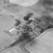 Oblique aerial view centred on the church and burial ground with manse, schoolhouse, farmsteading and road bridge adjacent, taken from the S.