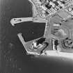 Oblique aerial view centred on the castle and coastal battery, with the harbour adjacent, taken from the SE.