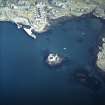 Oblique aerial view centred on the tower-house with the pier and town adjacent, taken from the SW.