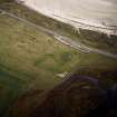 Oblique aerial view centred on the remains of the church and burial ground, taken from the W.