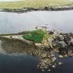 Oblique aerial view centred on the remains of the broch with the ruin of the building adjacent, taken from the N.