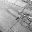 Oblique aerial view centred on the remains of the cairn, with the cottage and farmsteading adjacent, taken from the SSW.